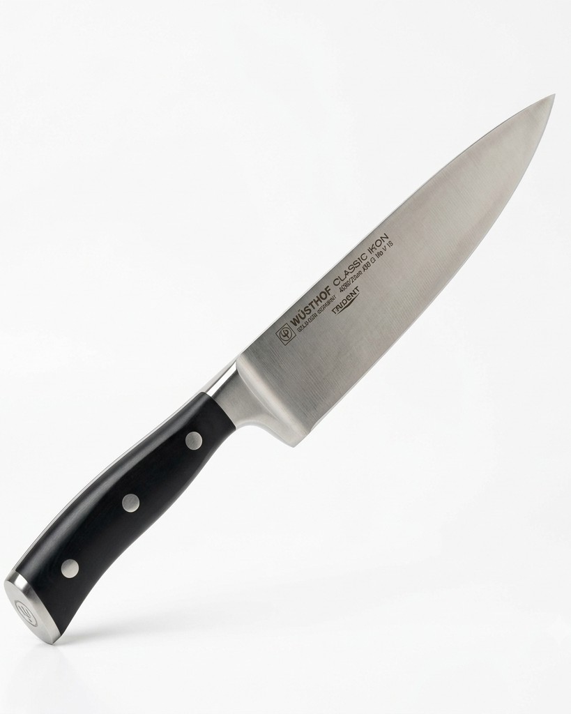 A forged Solingen chef's knife resting on a walnut board